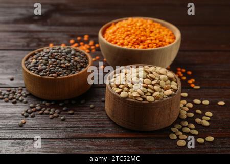 Différents types de lentilles dans des bols sur la table en bois, gros plan Banque D'Images