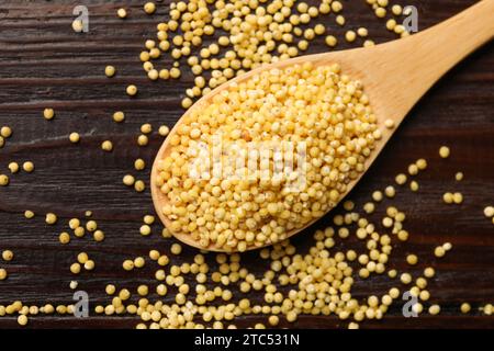 Cuillère avec gruaux de millet sur table en bois, vue de dessus Banque D'Images