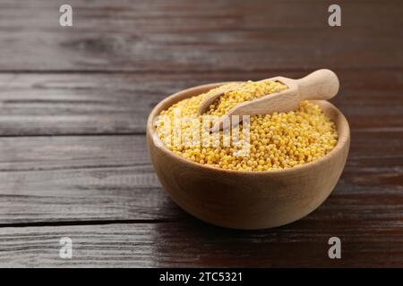 Gruaux de millet dans un bol et pelle sur une table en bois, espace pour le texte Banque D'Images
