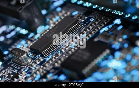 Microprocesseur sur une carte de circuit imprimé entouré d'éléments auxiliaires, rétroéclairé à travers la carte. Macrofto dans des couleurs sombres Banque D'Images
