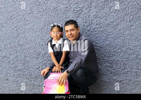 Un père célibataire divorcé va chercher sa fille de 4 ans en uniforme à l'école, les Latinos à la peau foncée parlent pour prévenir les abus et la violence Banque D'Images