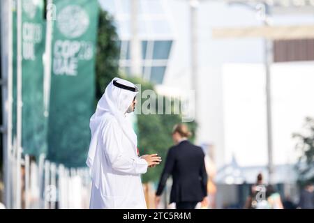 Dubaï, Émirats arabes Unis. 11 décembre 2023. Un homme traverse le terrain de la COP28 de la Conférence des Nations Unies sur les changements climatiques. Les principaux thèmes de la Conférence des Nations Unies sur les changements climatiques de cette année incluent le financement des dommages causés par les changements climatiques. Crédit : Hannes P. Albert/dpa/Alamy Live News Banque D'Images