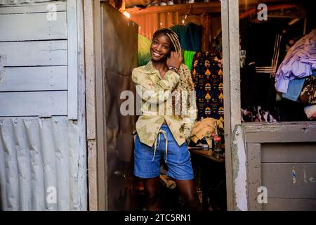 Nairobi, Kenya. 16 novembre 2023. Nadupoi Oreu, mannequin de 22 ans, pose pour une photo au stand de Richard Onyango vêtu d'une tenue conçue par Tatiana d'Afrowema en préparation du Just Fashion Day à l'Eco Fashion week Kenya le 16 novembre 2023 à Nairobi, Kenya. Afrowema (une marque sociale de mode éthique et durable née à Kibera, au Kenya, le plus grand bidonville d’Afrique, Afrowema contribue à l’autonomisation des artisans de cette communauté et crée de nouvelles opportunités d’emploi en utilisant des matériaux locaux neufs et usagés) a été fondée par Tatiana. Juste avant l'événement, Tatiana accompagnait b Banque D'Images