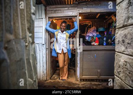 Nairobi, Kenya. 16 novembre 2023. Lucy Njeri, mannequin de 22 ans, pose pour une photo au stand de Richard Onyango vêtue d'une tenue conçue par Tatiana d'Afrowema en préparation du Just Fashion Day à l'Eco Fashion week Kenya le 16 novembre 2023 à Nairobi, Kenya. Afrowema (une marque sociale de mode éthique et durable née à Kibera, au Kenya, le plus grand bidonville d’Afrique, Afrowema contribue à l’autonomisation des artisans de cette communauté et crée de nouvelles opportunités d’emploi en utilisant des matériaux locaux neufs et usagés) a été fondée par Tatiana. Juste avant l'événement, Tatiana accompagné par Banque D'Images