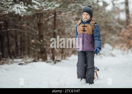 Garçon de six ans dans le paysage forestier d'hiver. Banque D'Images
