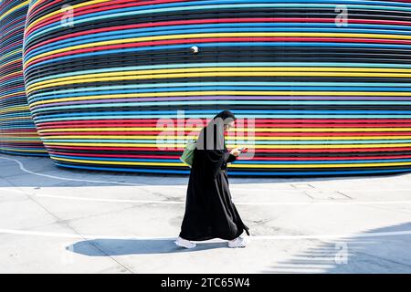 Dubaï, Émirats arabes Unis. 11 décembre 2023. Une femme marche devant l’ancien pavillon russe à l’EXPO 2020 sur le terrain de la COP28 du sommet des Nations Unies sur le climat. Les principaux thèmes de la conférence des Nations unies sur le climat de cette année incluent le financement des dommages causés par le changement climatique. Crédit : Hannes P. Albert/dpa/Alamy Live News Banque D'Images