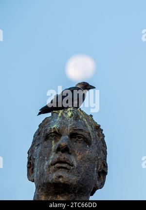 Lune et Crow, oiseau assis sur la statue en bronze de l'homme épiphanique, situé dans la ville d'Ohrid Macédoine été 2023 Banque D'Images