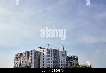 Fragment de grue à tour, construction d'une maison. Bâtiment en béton en construction. Chantier de construction Banque D'Images