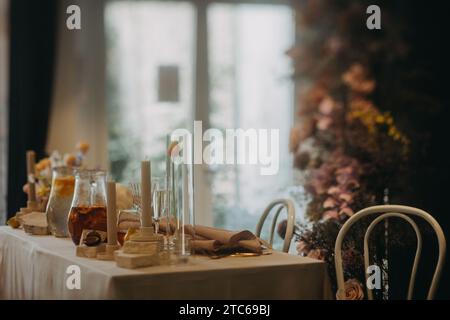 Réglage de table élégant, propre et facile pour fête intérieure, réception de mariage avec luxe, grande décoration de fleur sur le mur. Table d'événement spécial mise en place avec Banque D'Images