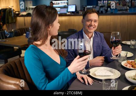 Heureux homme et femme buvant du vin tout en célébrant Noël Banque D'Images