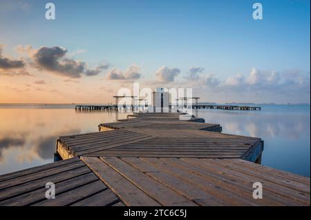 Jetée en bois, atteignant la Mar Menor, dans le sud de l'Espagne, au lever du soleil. Longue exposition pour lisser la mer Banque D'Images