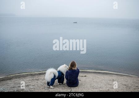 Fille marche avec un chien blanc moelleux Samoyed dans la nature Banque D'Images