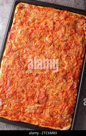 Sfincione ou pizza de style sicilien avec une croûte de levure maison et sauce tomate-oignon, fromage et anchois sur le dessus closeup sur une plaque de cuisson sur le ta Banque D'Images