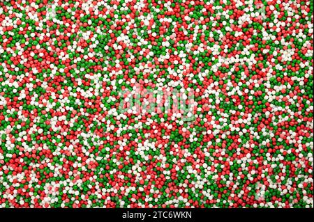 Saupoudrages colorés faits de minuscules boules de sucre. Mélange vert, rouge et blanc de nonpareils. Des centaines et des milliers décoratifs faits de sucre et d'amidon. Banque D'Images