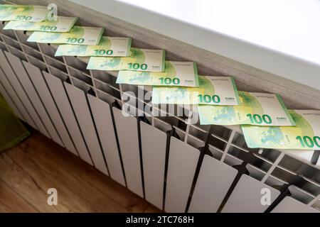 Le concept de payer pour le chauffage dans les maisons avec un climat froid. L'argent comptant est couché sur un radiateur en métal blanc près de la fenêtre. Banque D'Images