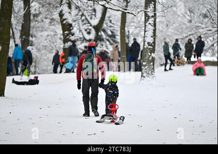 LVIV, UKRAINE - 10 DÉCEMBRE 2023 - Un homme et un garçon tirant un traîneau orientable gravissent une colline, Lviv, ouest de l'Ukraine. Banque D'Images