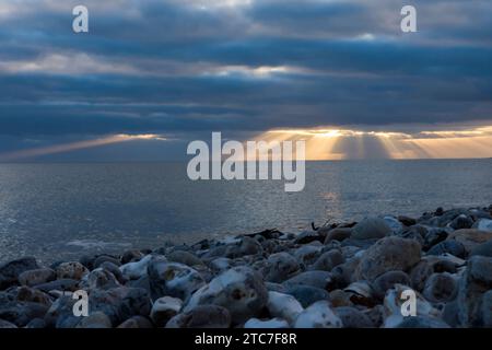 rayons de soleil brillant à travers gap dans des nuages noirs sombres sur l'horizon de la mer. Hiver, novembre, Devon, Royaume-Uni Banque D'Images