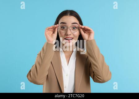 Femme surprise portant des lunettes sur fond turquoise Banque D'Images