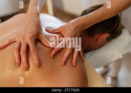 Gros plan d'un massothérapeute exerçant une pression sur le dos d'un client. Image conceptuelle du salon de beauté Wellness Hotel Banque D'Images