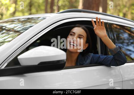 Heureuse jeune femme regardant par la fenêtre de la voiture, vue de l'extérieur. Bon voyage Banque D'Images