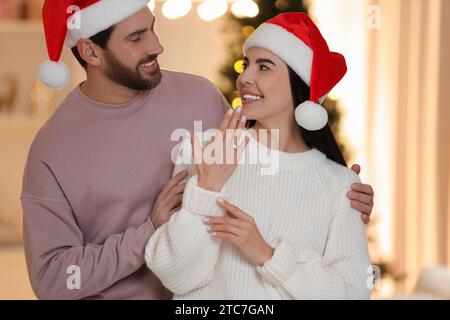 Faire une proposition. Femme heureuse avec bague de fiançailles et son fiancé à la maison à Noël Banque D'Images