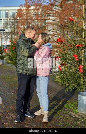 Portrait de jeunes gens attrayants, couple charmant bénéficiant de l'atmosphère chaleureuse sur la foire dans la veille de Noël. Passer du temps ensemble. Concept de trad nationale Banque D'Images