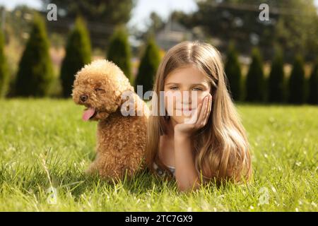 Belle fille avec chien mignon Maltipoo sur la pelouse verte dans le parc Banque D'Images