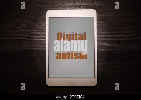 Tablette avec phrase Digital Autism sur table en bois, vue de dessus. Comportement addictif Banque D'Images