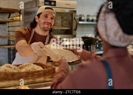 Souriant boulanger caucasien passant la commande à emporter à une cliente inconnue, concentrez-vous sur l'homme Banque D'Images