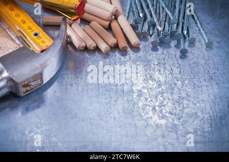Clous et chevilles de construction de compteur en bois de marteau à griffes sur le concept de maintenance de fond métallique rayé Banque D'Images