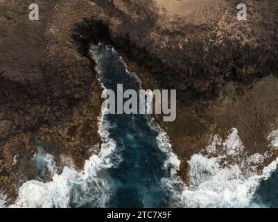 Vue aérienne d'un canal d'eau étroit entre un terrain accidenté menant à l'océan sur l'île de fuerteventura Banque D'Images