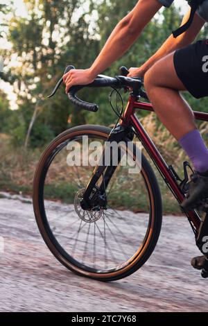 Gros plan de cycliste sur vélo de gravier professionnel sur route de campagne au coucher du soleil. Banque D'Images