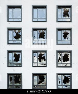 Façade de maison résidentielle avec fenêtres cassées et dommages causés par des fragments de mines et d'obus. Banque D'Images