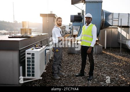 Hommes ingénieurs debout et serrant la main sur le toit Banque D'Images