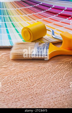 Brosse à rouleau de peinture et ventilateur de pantone brillant sur le concept d'entretien de panneau de bois Banque D'Images