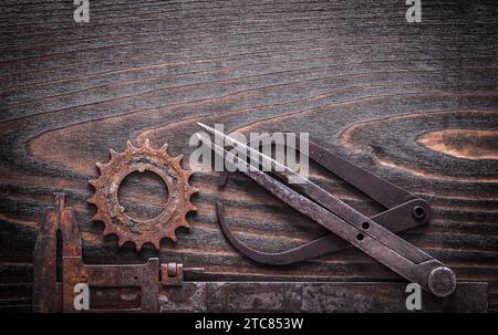 Étriers de mesure antiques rouillés avec roue dentée sur fond en bois sombre vintage concept de construction vue de dessus Banque D'Images