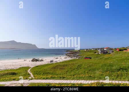 Le temps ensoleillé illumine la baie immaculée de Jusnesvika sur la plage de Rambergstranda à Flakstadoya, Lofoten, avec un couple se dirigeant pour une baignade Banque D'Images