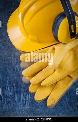 Casque de protection auditive de sécurité et gants de protection en cuir jaune sur le concept de construction de fond métallique Banque D'Images