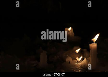 Bougies allumées scintillant et fondant en silence dans une église. Banque D'Images