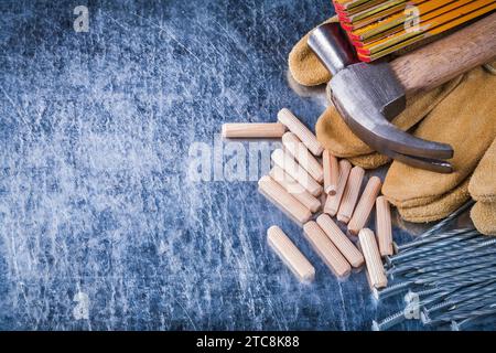 Gants de sécurité en cuir de marteau de griffe compteur en bois tas de clous métalliques et chevilles sur le concept de construction de fond métallique rayé Banque D'Images
