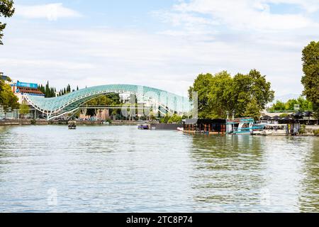 Tbilissi, Géorgie - 26 septembre 2023 : Rivière Kura et Pont moderne de la paix dans la ville de Tbilissi le jour ensoleillé de l'automne Banque D'Images