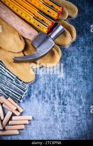 Marteau gants de protection en cuir pile de mètre en bois de clous métalliques et chevilles sur surface métallique rayée concept de construction vue de dessus Banque D'Images