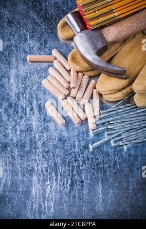 Marteau gants de protection en cuir compteur en bois tas de clous métalliques et chevilles sur le concept de construction de fond métallique rayé Banque D'Images