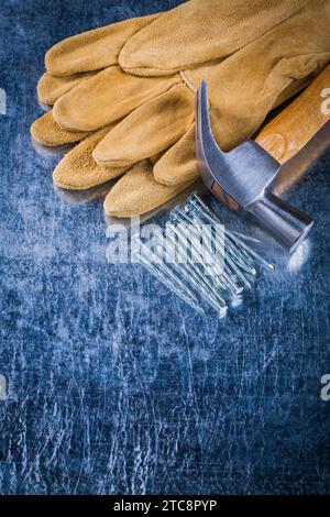 Paire de gants de protection en cuir tas de clous de construction et marteau de griffe sur le concept de bâtiment de fond métallique rayé Banque D'Images