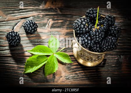 Framboises sucrées dans un seau sur une vieille planche de bois Banque D'Images