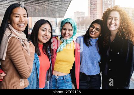 Diverses amies féminines ayant du plaisir togehter sur la rue de la ville. Groupe de personnes multiraciales souriant et serrant à la caméra Banque D'Images