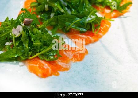 Sashimi de sushi au carpaccio de saumon frais avec salade de roquette à la roquette et câpres sur le dessus Banque D'Images
