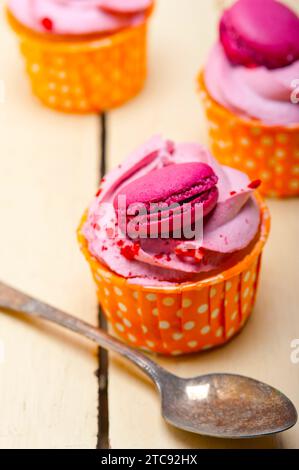 Gâteau aux fruits frais et à la crème de baies roses avec macaron sur une table en bois rustique Banque D'Images