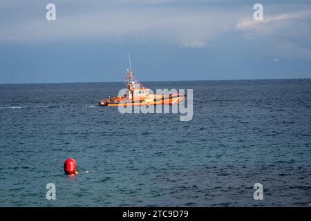 Bateau de sauvetage orange sur une mer bleue calme avec une bouée au premier plan. Banque D'Images