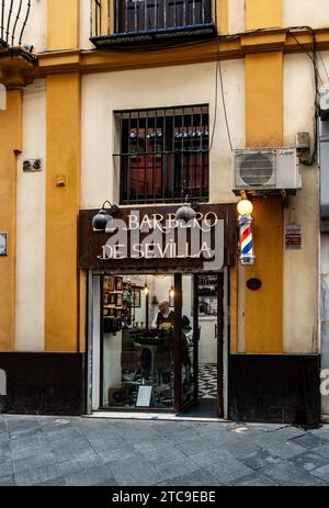 Entrée traditionnelle d'un salon de coiffure à Séville, en Espagne, avec un poteau rayé emblématique, avec un nom d'opéra. Banque D'Images